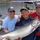Three men and their Chinook salmon catch standing on the dock
