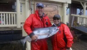 fish-13 A man and a woman in fishing clothes pose with their Chinook salmon catch in front of King Pacific Lodge