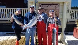 fish-14 Three men and a woman pose in front of King Pacific Lodge with their King salmon catch