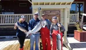 fish-15 Three men and a woman pose in front of King Pacific Lodge with their King salmon catch