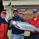 Three men pose in front of King Pacific Lodge with their King salmon catch