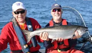 fish-17 Two men show off their Chinook salmon catch on a boat in the water