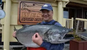 fish-20 A man poses holding his Chinook salmon catch in front of King Pacific Lodge