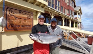 Two men holding Chinook salmon in front of King Pacific Lodge