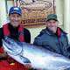 Two men and a Chinook salmon in front of King Pacific Lodge