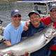 Three men and their Chinook salmon catch standing on the dock