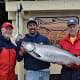 Three men pose in front of King Pacific Lodge with their King salmon catch