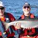 Two men show off their Chinook salmon catch on a boat in the water