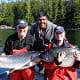Three men hold their two Chinook salmons near the dock